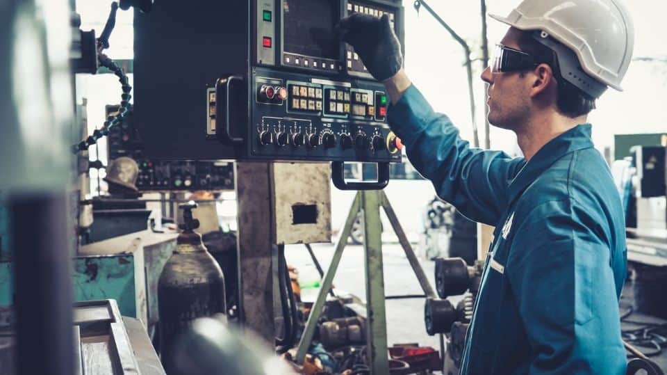 A man in work clothes operating a device in a factory
