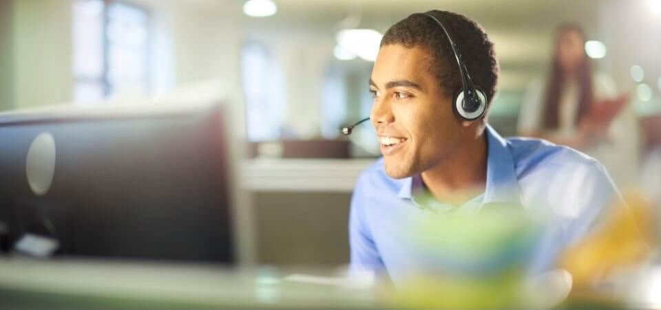Konsultant Customer Service siedzący w słuchawkach przy monitorze