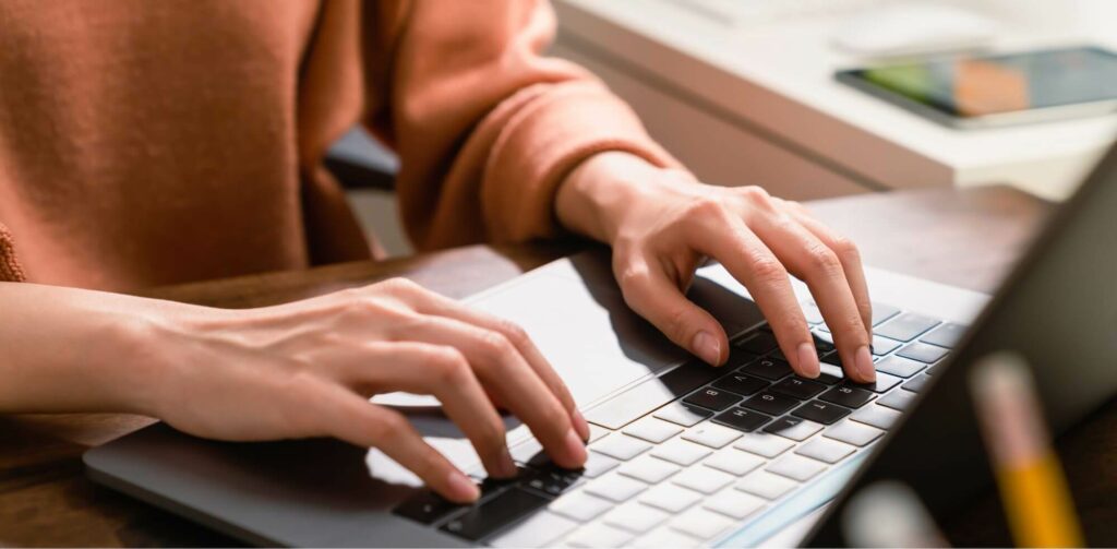 person working on a laptop, close-up of hands and keyboard