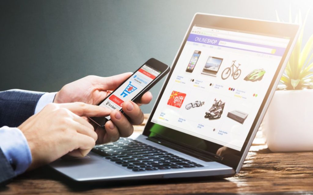 osoba przegląda ofertę sklepu internetowego na komputerze oraz na smartfonie