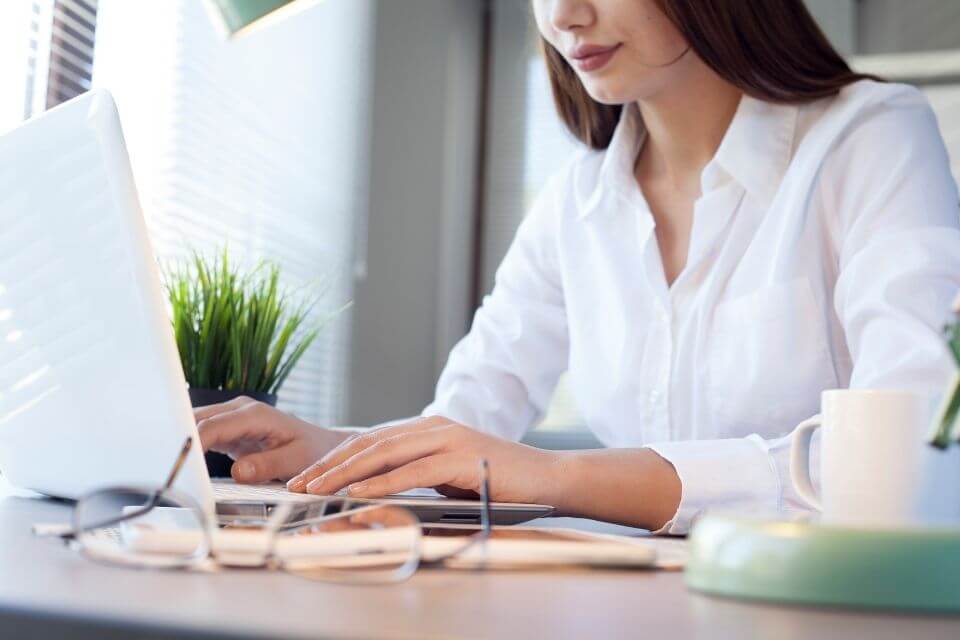 Photo of a woman specializing in indirect sales, working on a laptop computer  